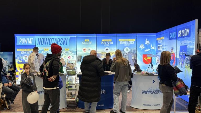 Grupa ludzi na tle banerów.jpeg